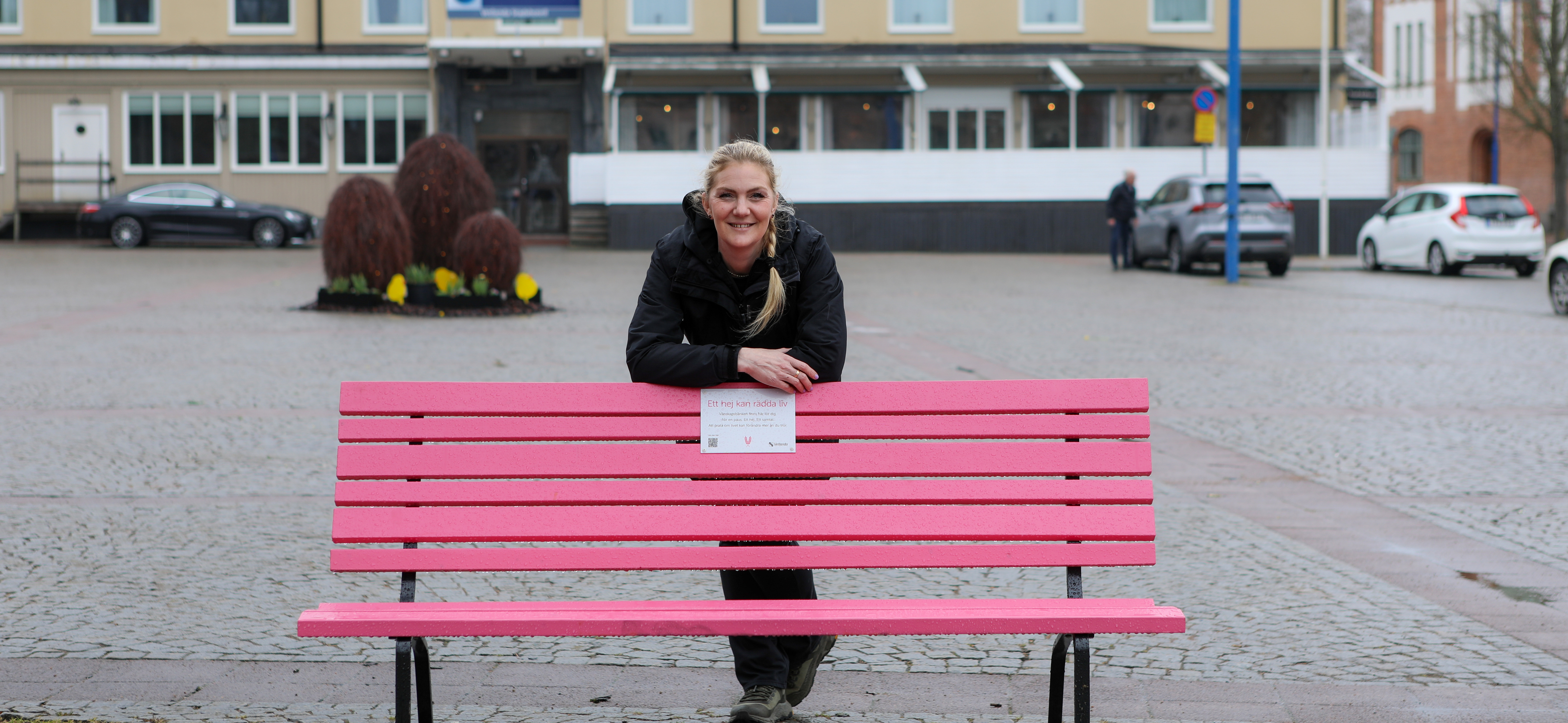 Mikaela lutad över en rosa bänk.