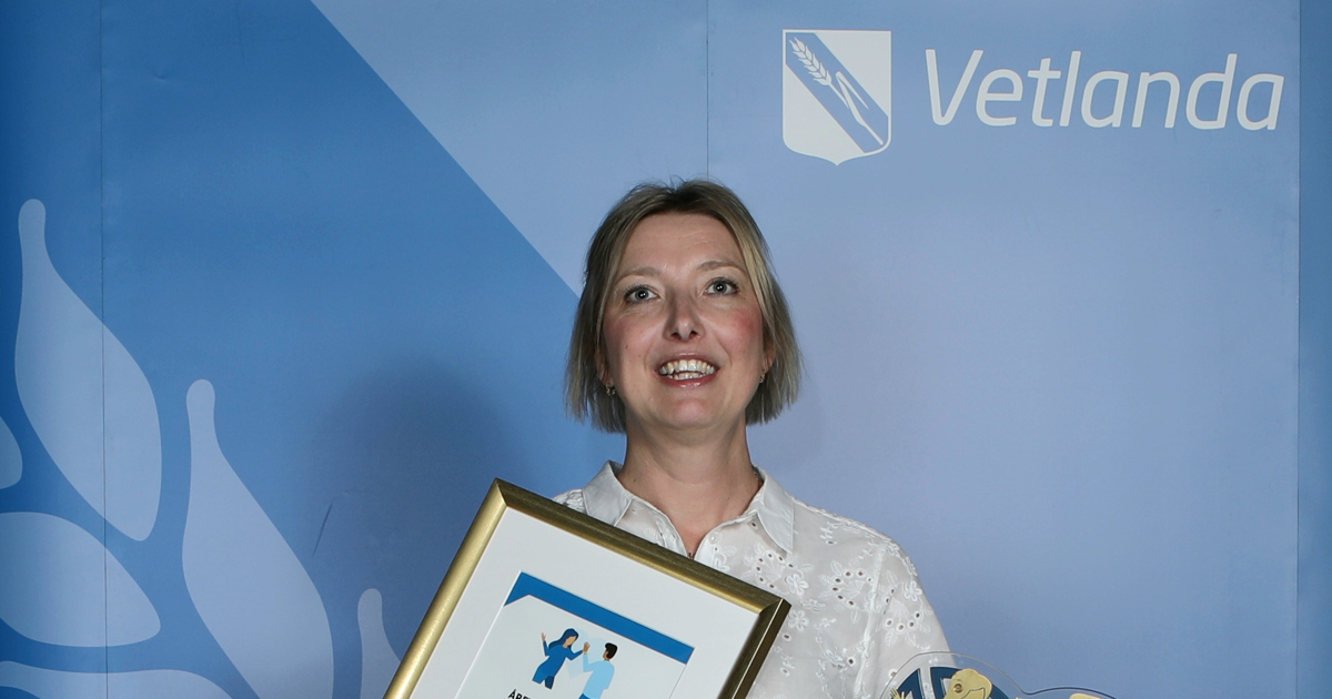 En kvinna står framför en kuliss och håller i en plakett.