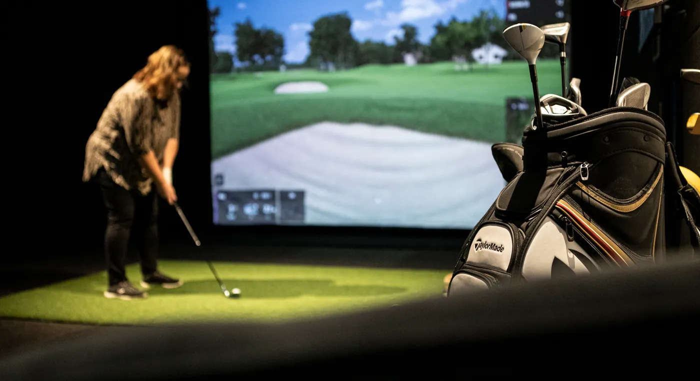 En kvinna som spelar golf framför en tv-apparat.