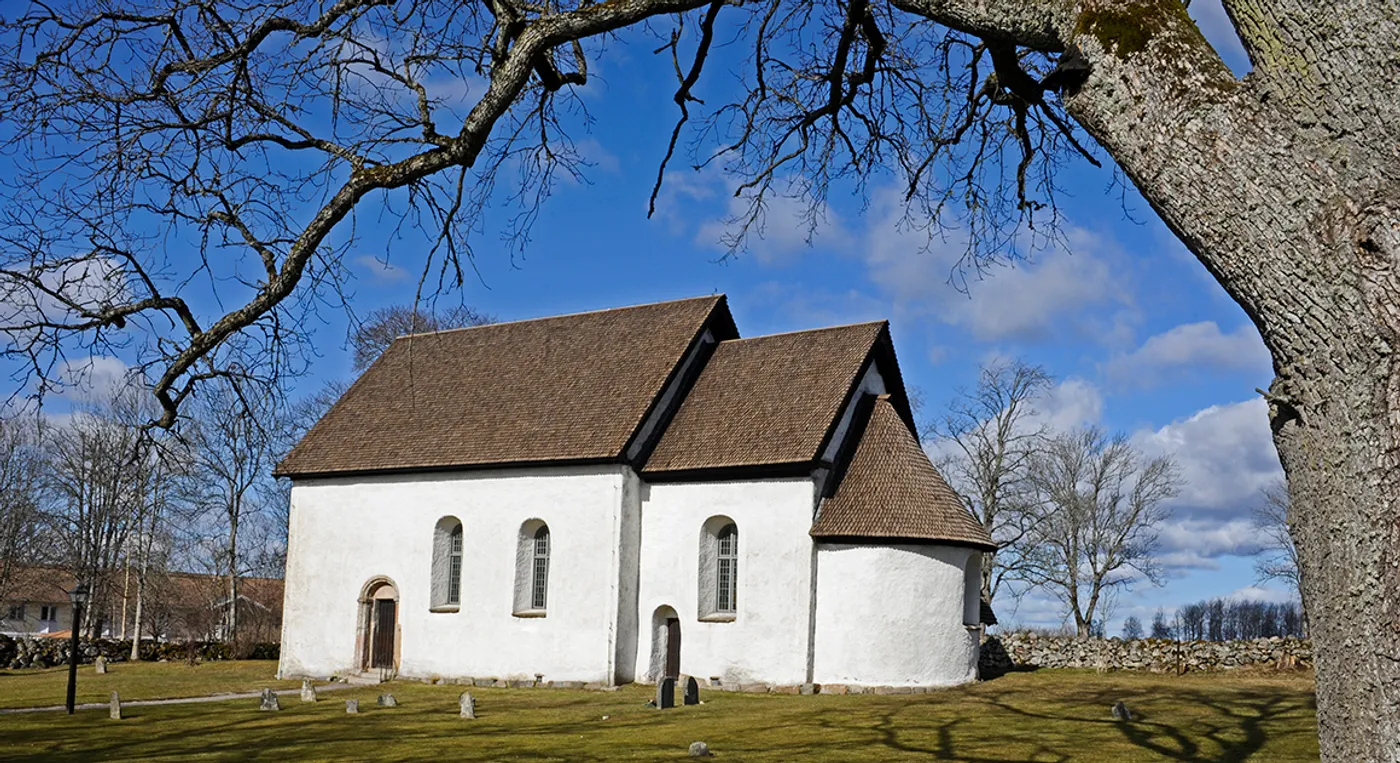 En vit kyrka med ett brunt tak av takspån.