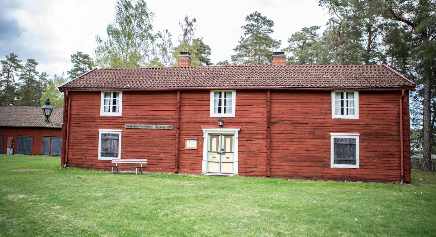 En röd byggnad med en bänk framför sig.