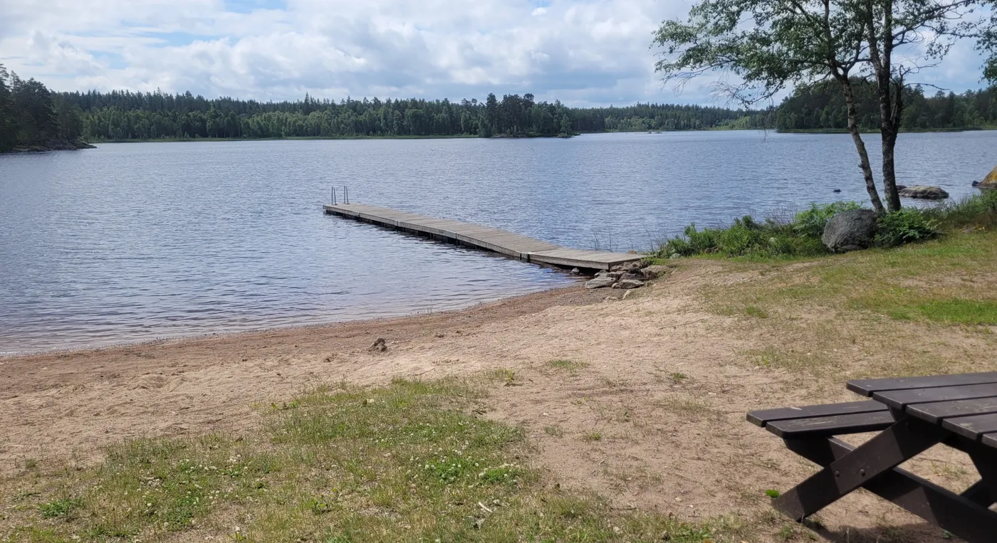 En träbänk som står vid en vattendrag.