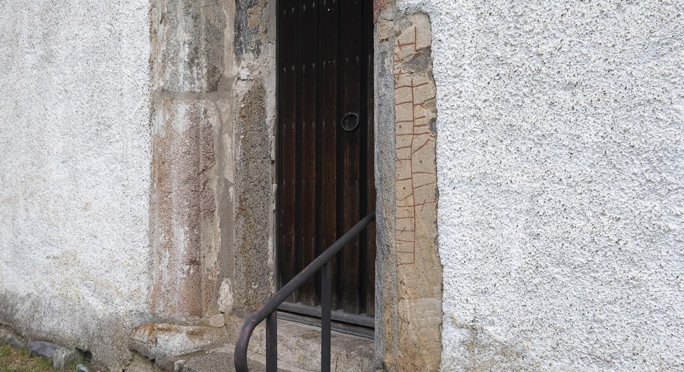 En dörröppning med runsten vid sidan.