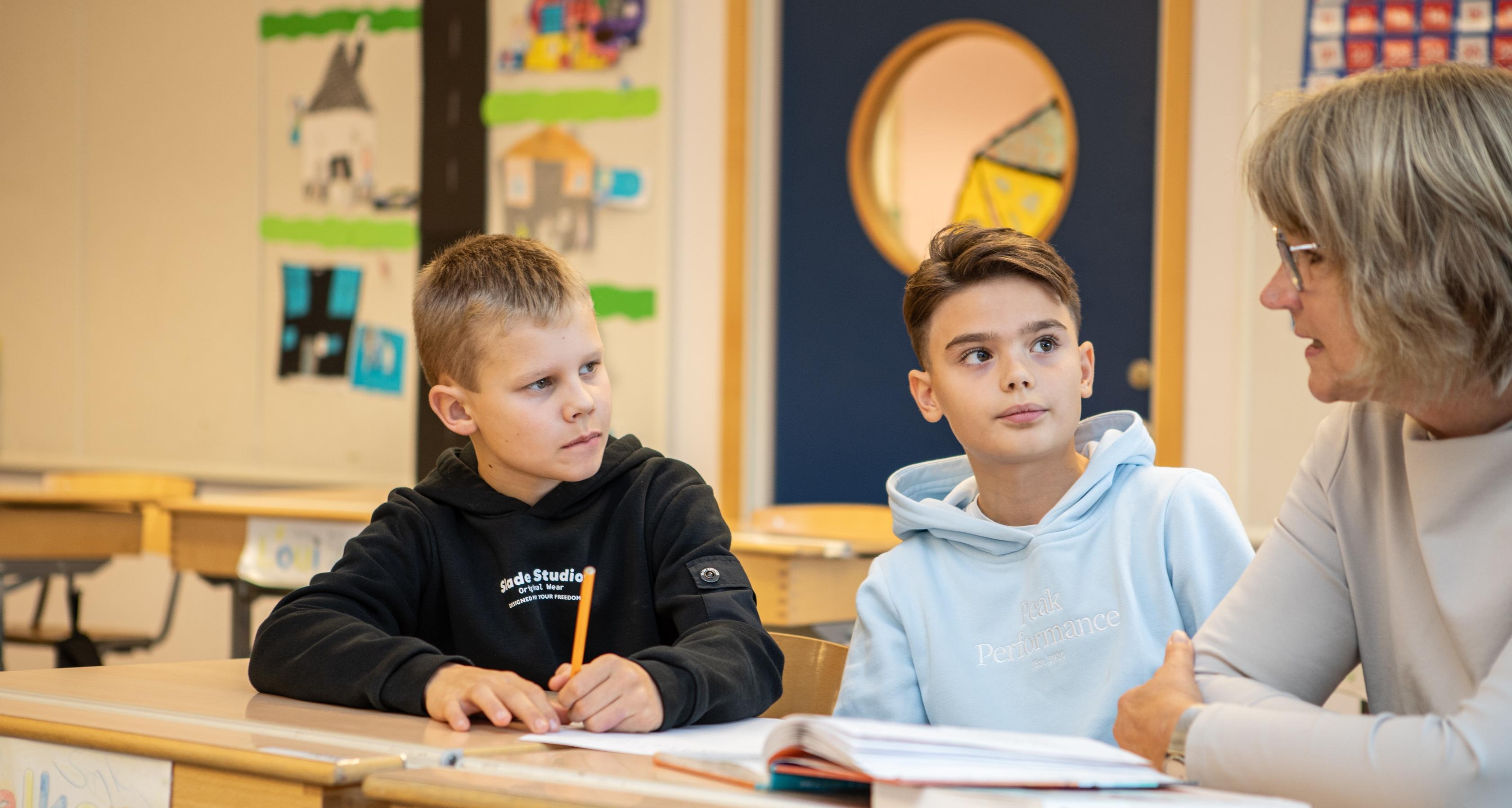 En senior i skolan pratar med två elever.