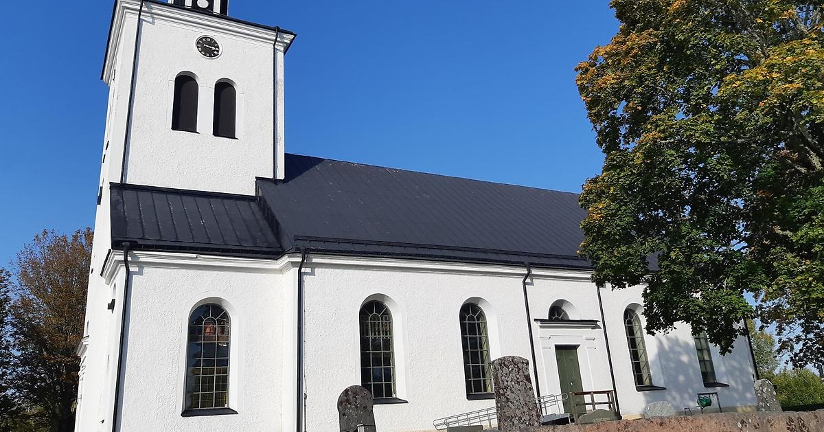 Björkö stora vita kyrka sedd från sidan, tornet till vänster och ett stort svart tak till höger.