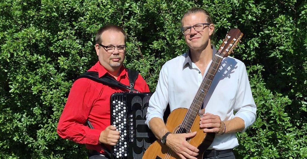 Två män som håller dragspel respektive gitarr i famnen