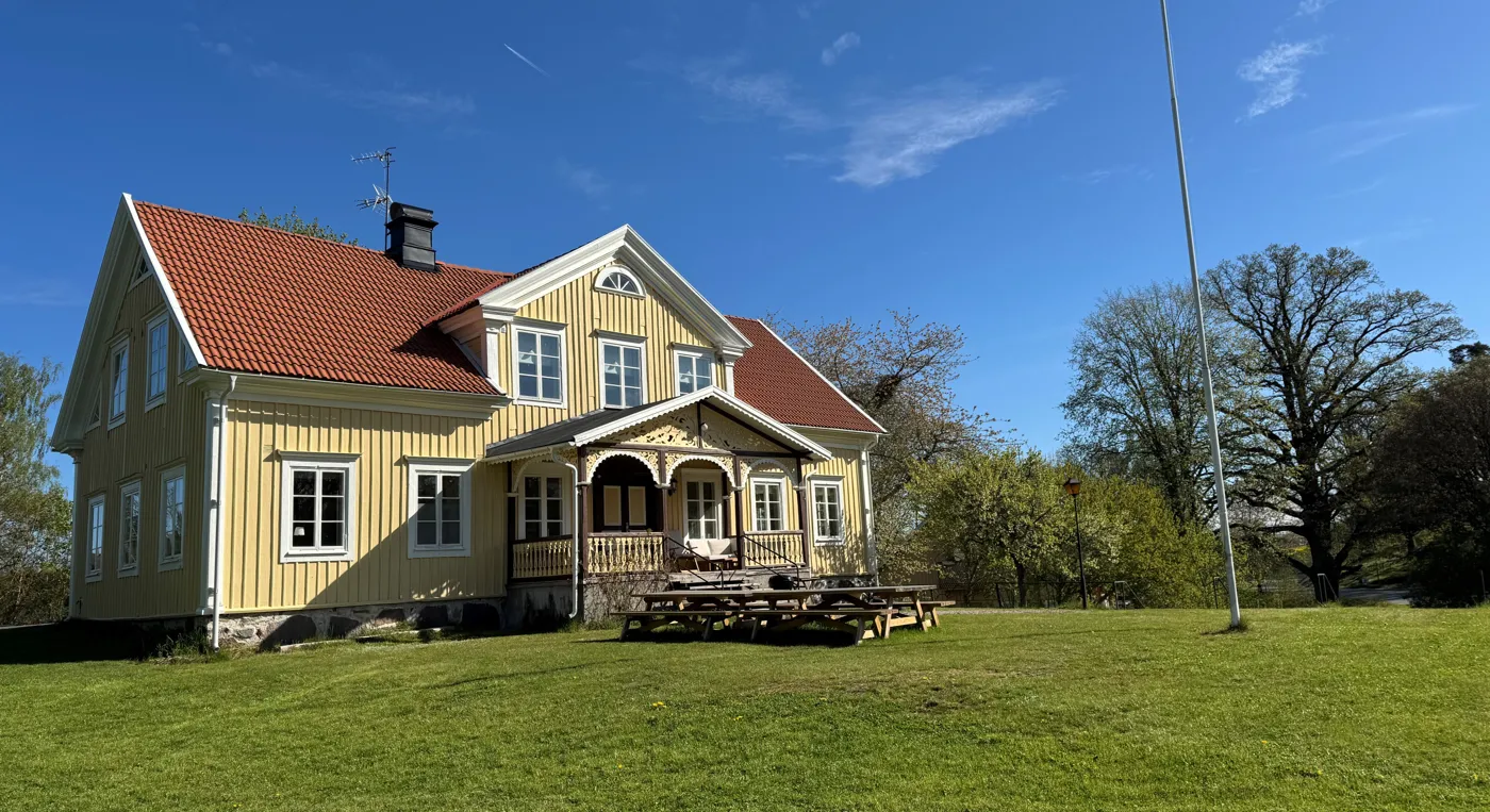 Ett gult hus med rött tak och ett picknickbord framför.