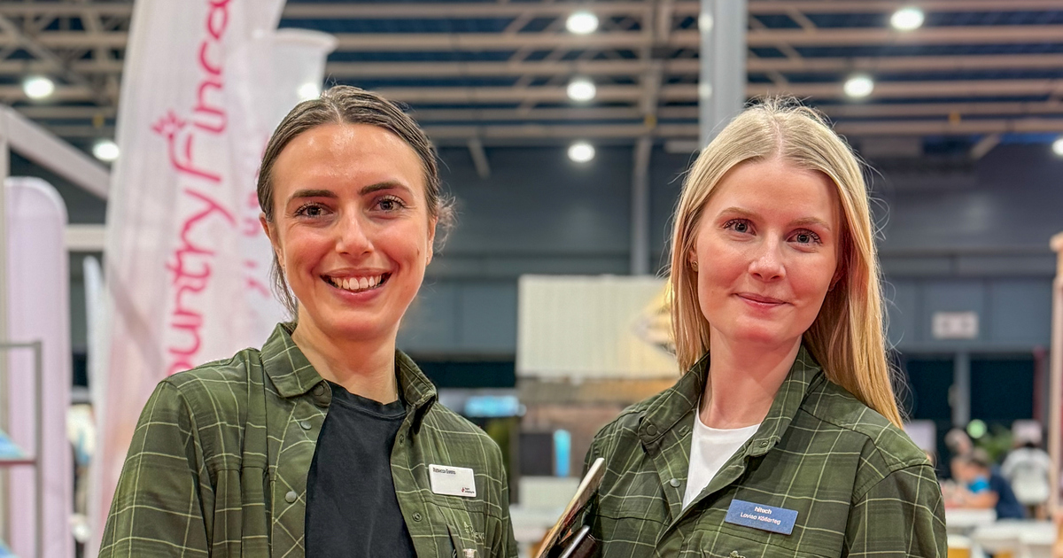 Två kvinnor i gröna skjortor i mässhallen i Utrecht.