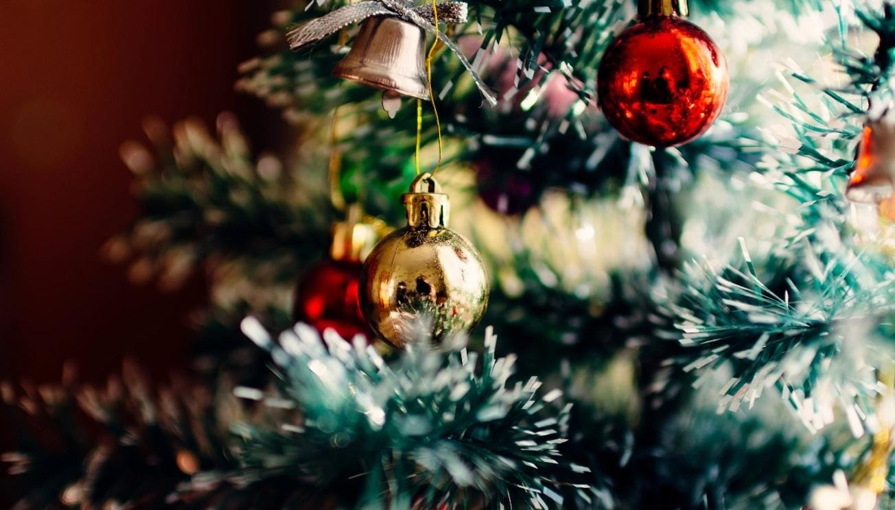 Glittrande detalj av julgran med röda och guldiga kulor