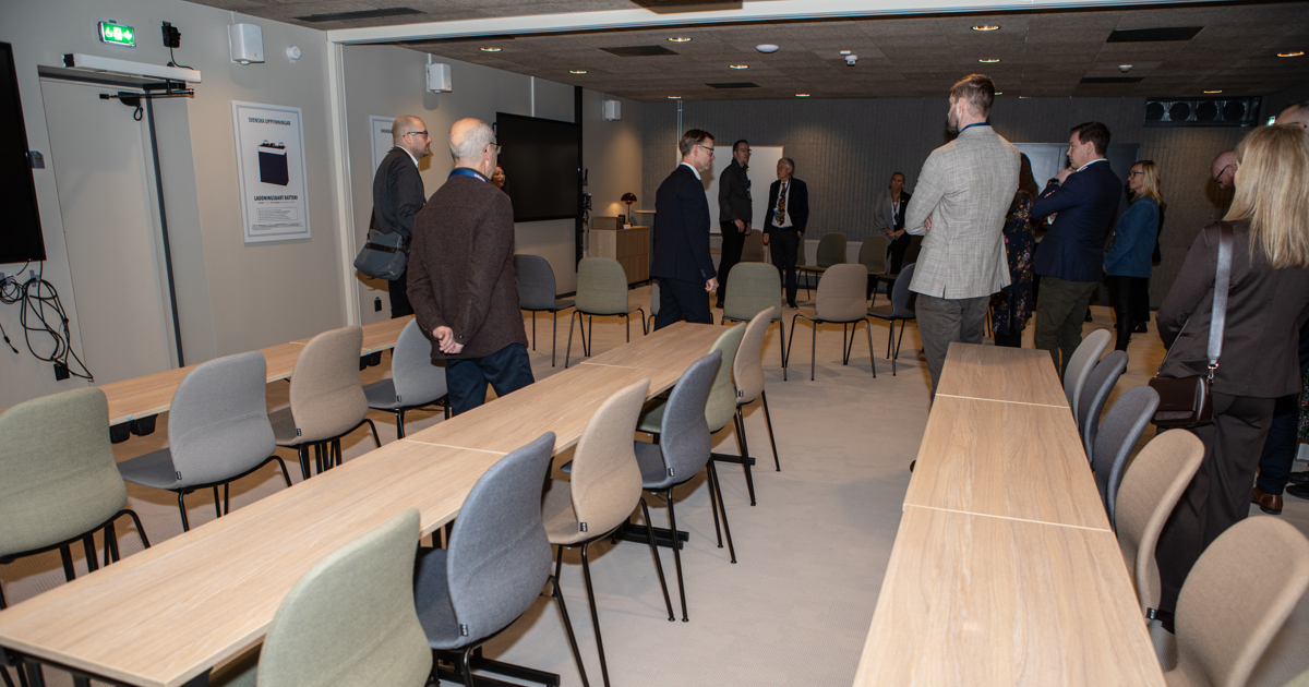 En samling människor står i ett konferensrum.