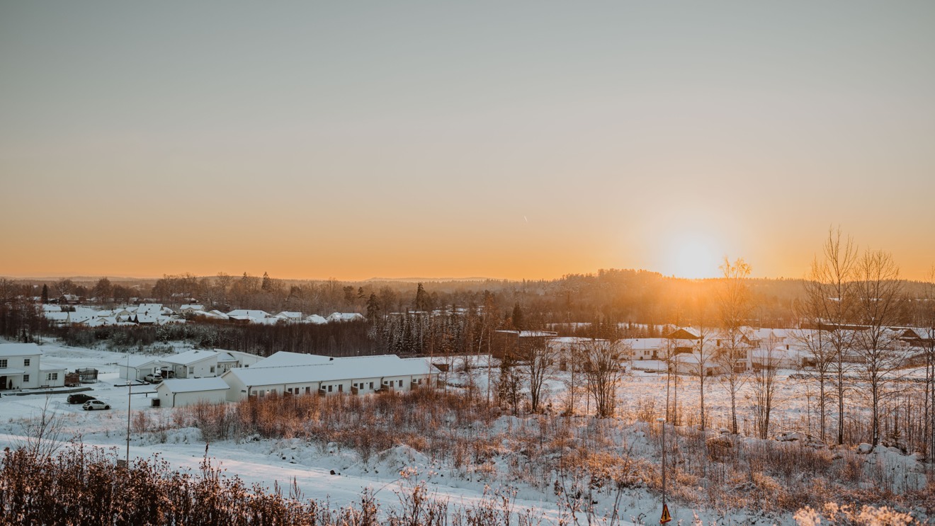 Vy över bostad- och naturområde en solig vinterdag.