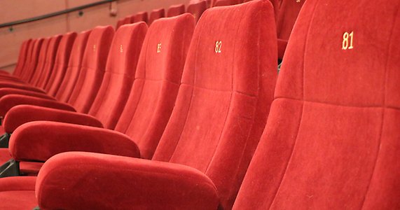En rad med röda stolar i en biosalong.