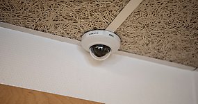 En övervakningskamera monterad i taket i ett rum.