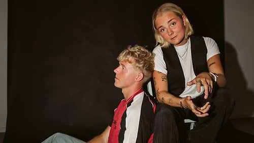 Bild på syskonen Anna och Marcus Claesson, sittande mot en mörk vägg.
